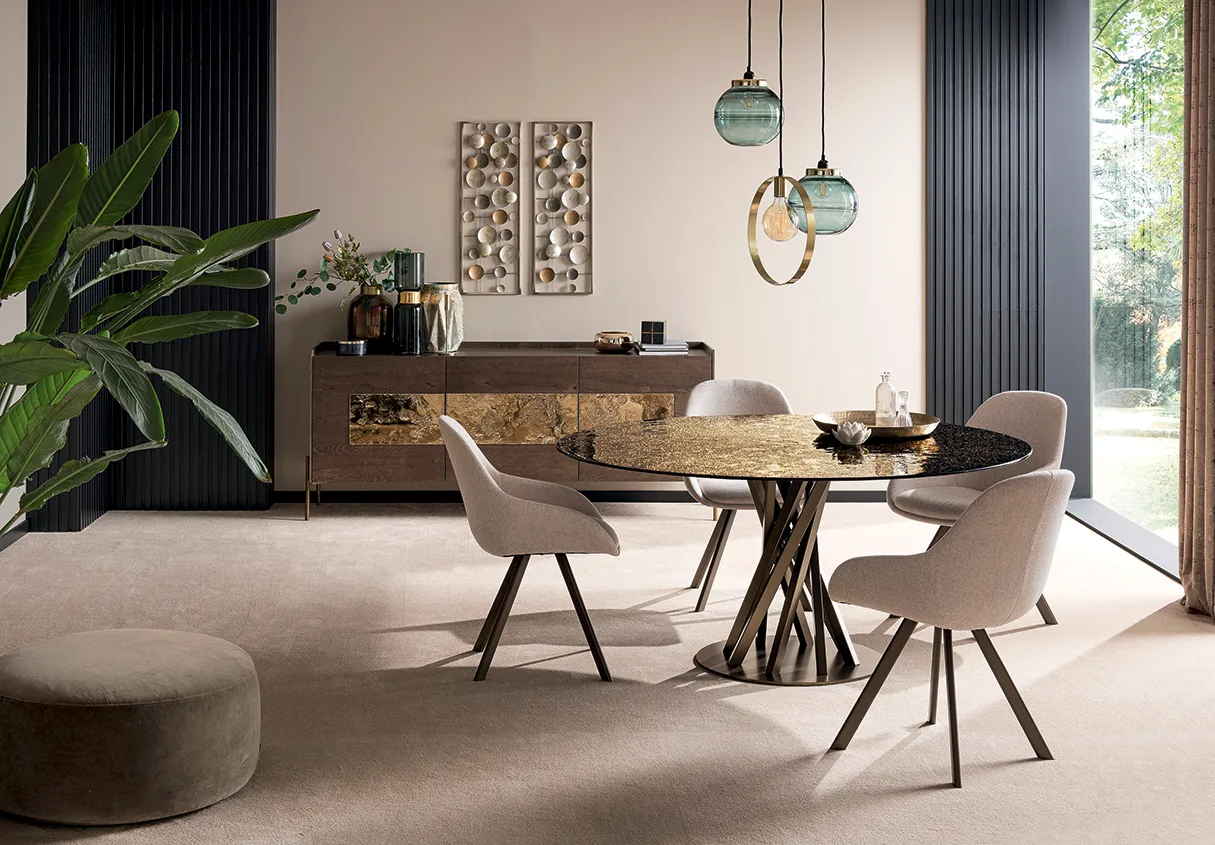 Zona pranzo elegante con tavolo rotondo in vetro e metallo, sedie imbottite, credenza in legno e lampade a sospensione in vetro verde