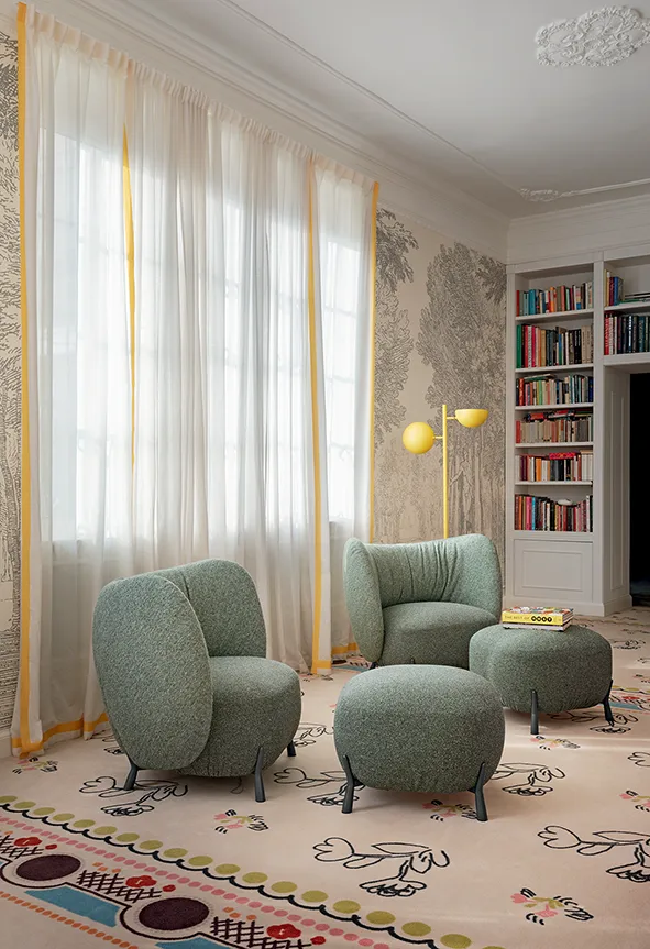 Angolo lettura con poltrone e pouf in tessuto verde salvia, libreria a incasso, tende leggere e tappeto decorativo